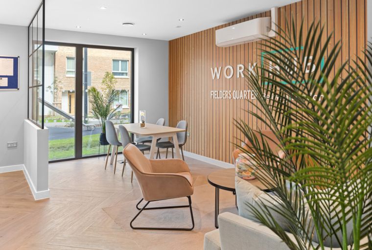A modern office space with a dining table, chairs, and a wood-paneled wall.