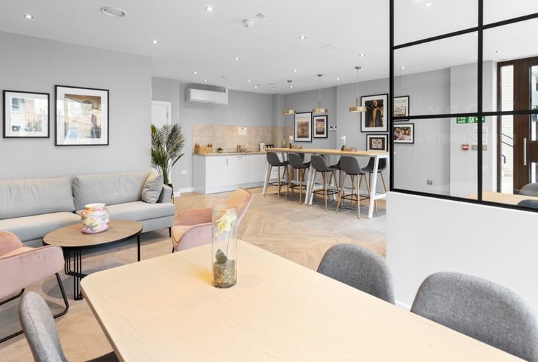 A communal living area with a sofa, chairs, and a kitchen with bar stools.