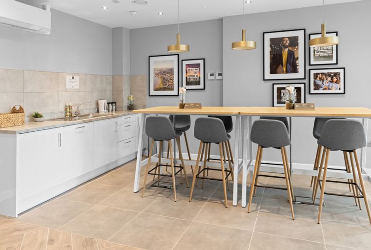 A communal kitchen with a long island, bar stools, and a kitchenette.