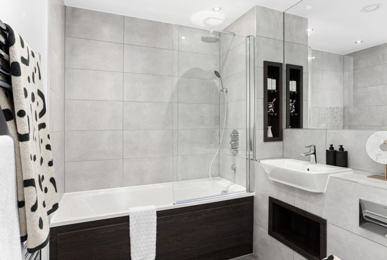 A modern bathroom with a bathtub, sink, and tiled walls.