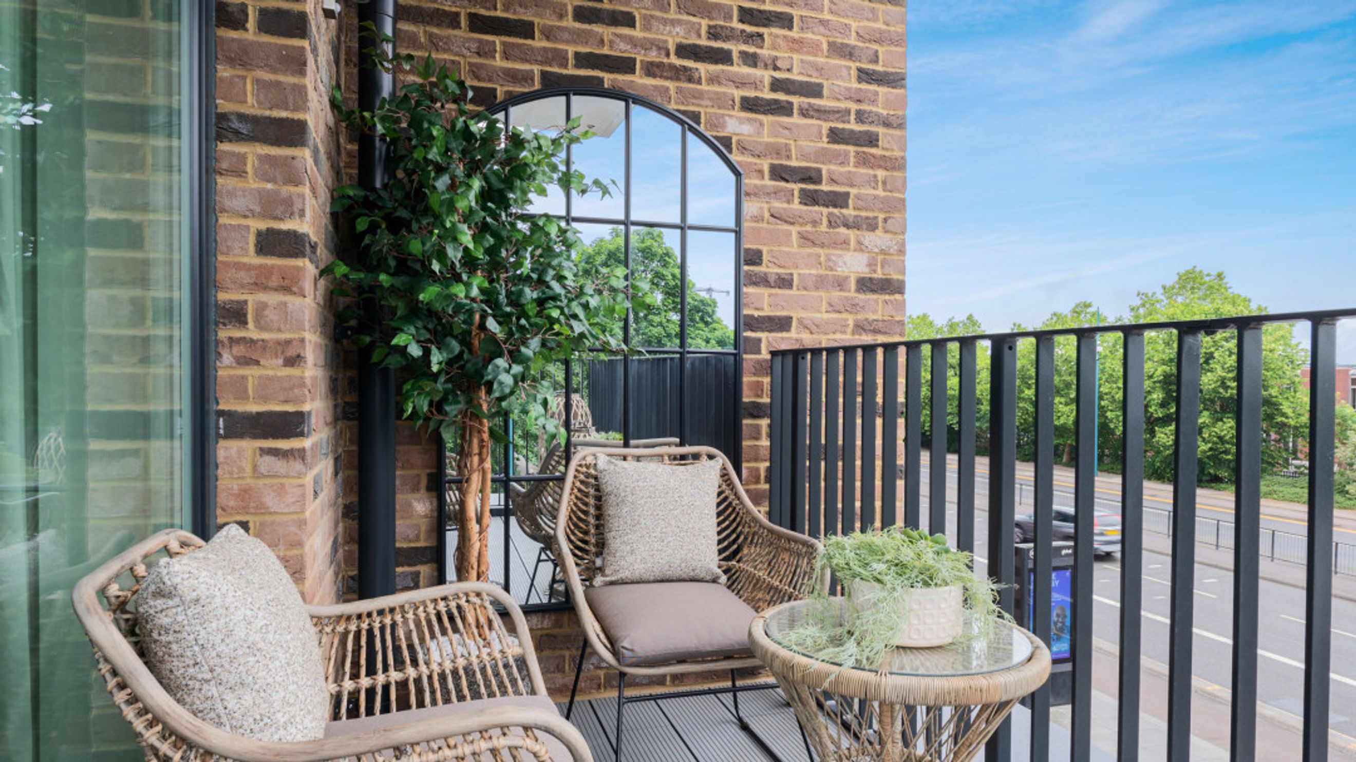 A balcony with two chairs, a table, and a plant.