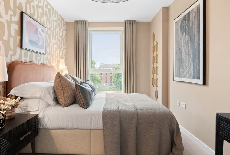 A bedroom with a bed, pillows, lamps, and a window.