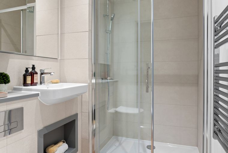 A bathroom with a sink, shower, and heated towel rail.