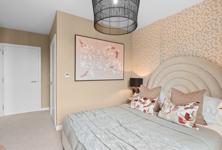 A bedroom with a bed, pillows, a blanket, a headboard, a lamp, and artwork.