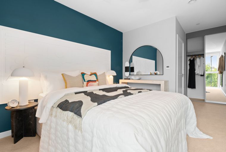 A bedroom with a bed, bedside table, lamp, and mirrored wardrobe.