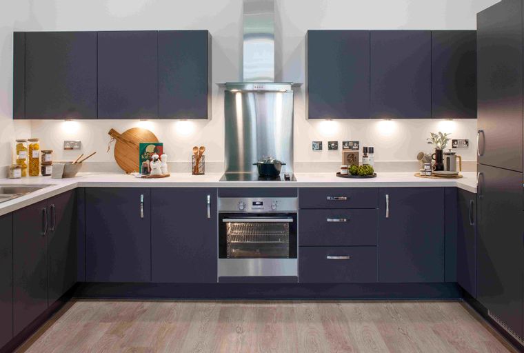 A modern U-shaped kitchen with dark cabinets, a stainless steel range hood, and a built-in oven.