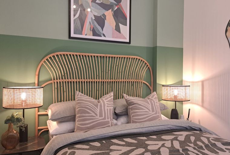 A bedroom with a bed, headboard, pillows, and bedside lamps.