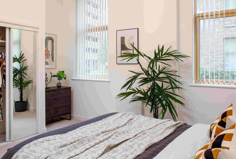 A bedroom with a bed, closet, dresser, and windows.
