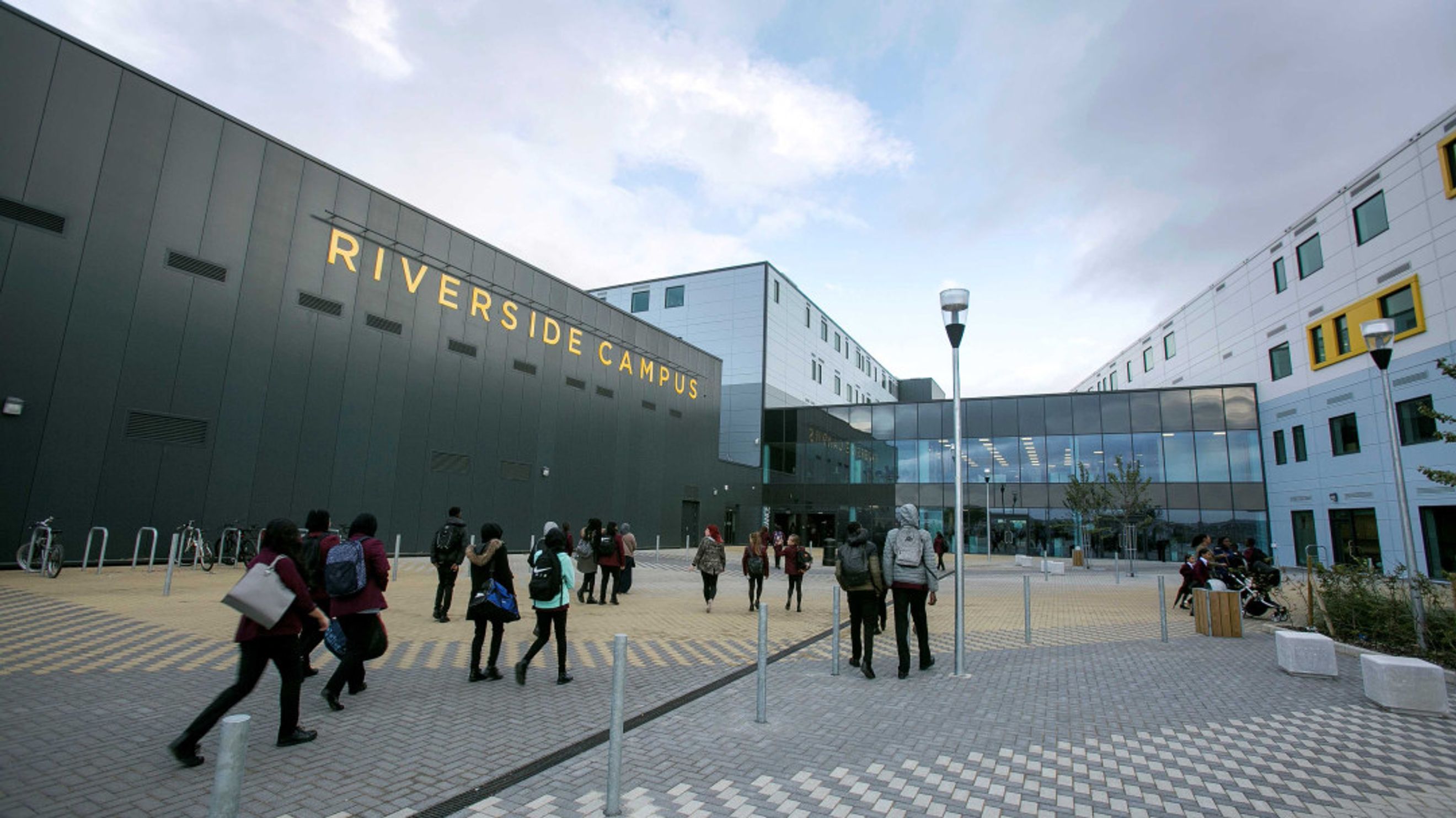 A modern campus building with 'RIVERSIDE CAMPUS' signage and students walking outside.