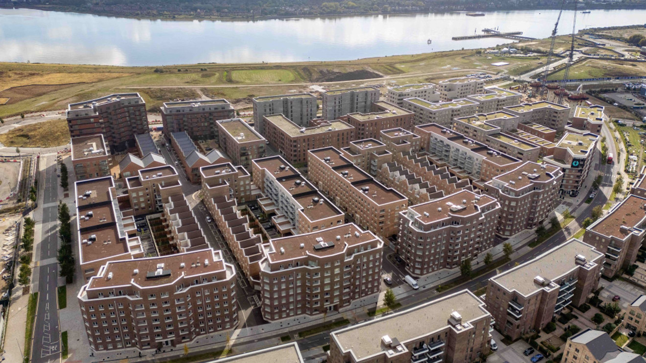 An aerial view of a modern residential complex with multiple buildings near a body of water.