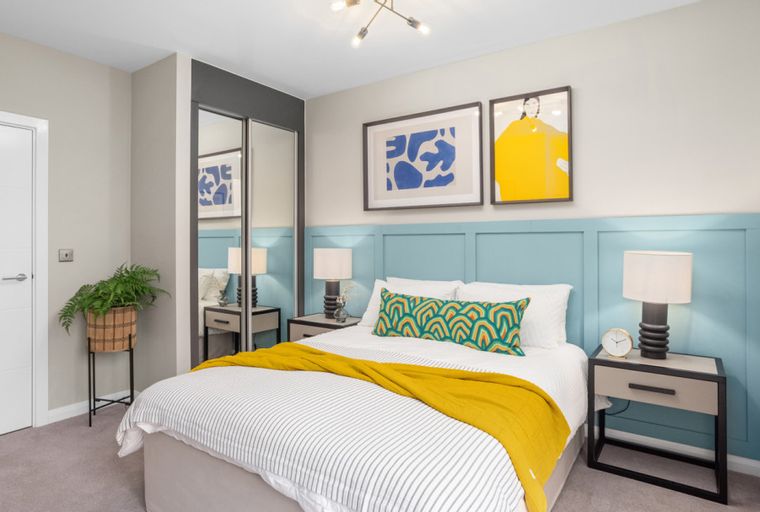 A bedroom with a bed, nightstands, and artwork on the wall.