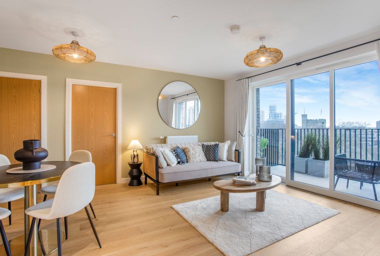 A living and dining area with a sofa, coffee table, dining table, chairs, and a balcony view.