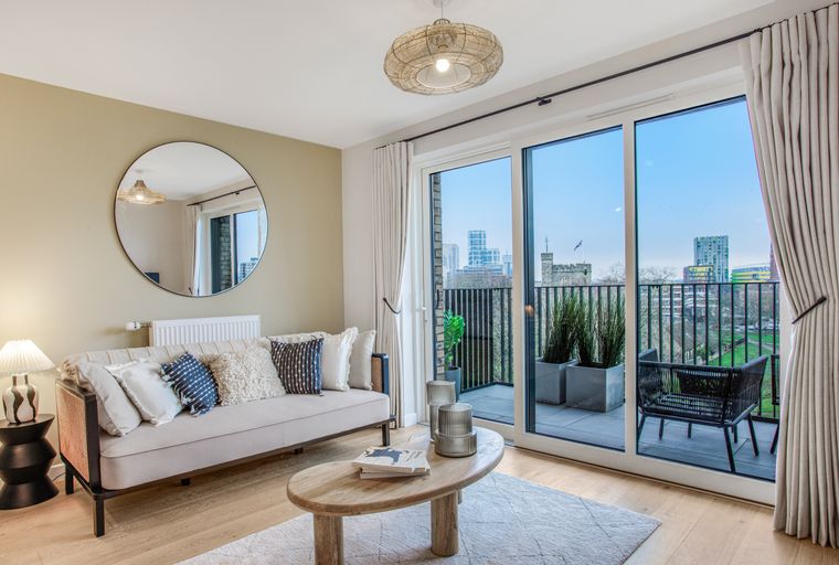 A living room with a sofa, coffee table, and large glass doors leading to a balcony.