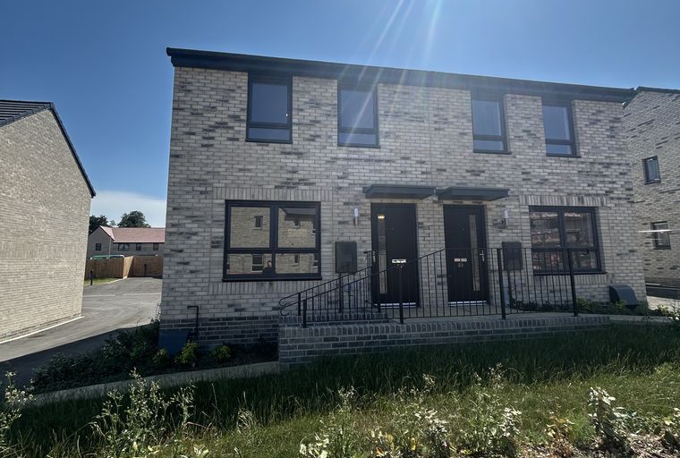 A pair of modern, two-story townhouses with brick exteriors and black doors and windows.