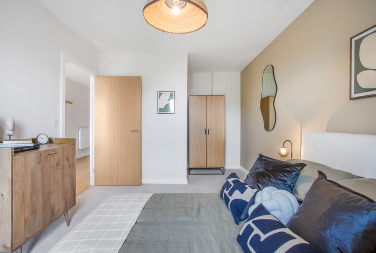 A bedroom with a bed, dresser, wardrobe, and a mirror.