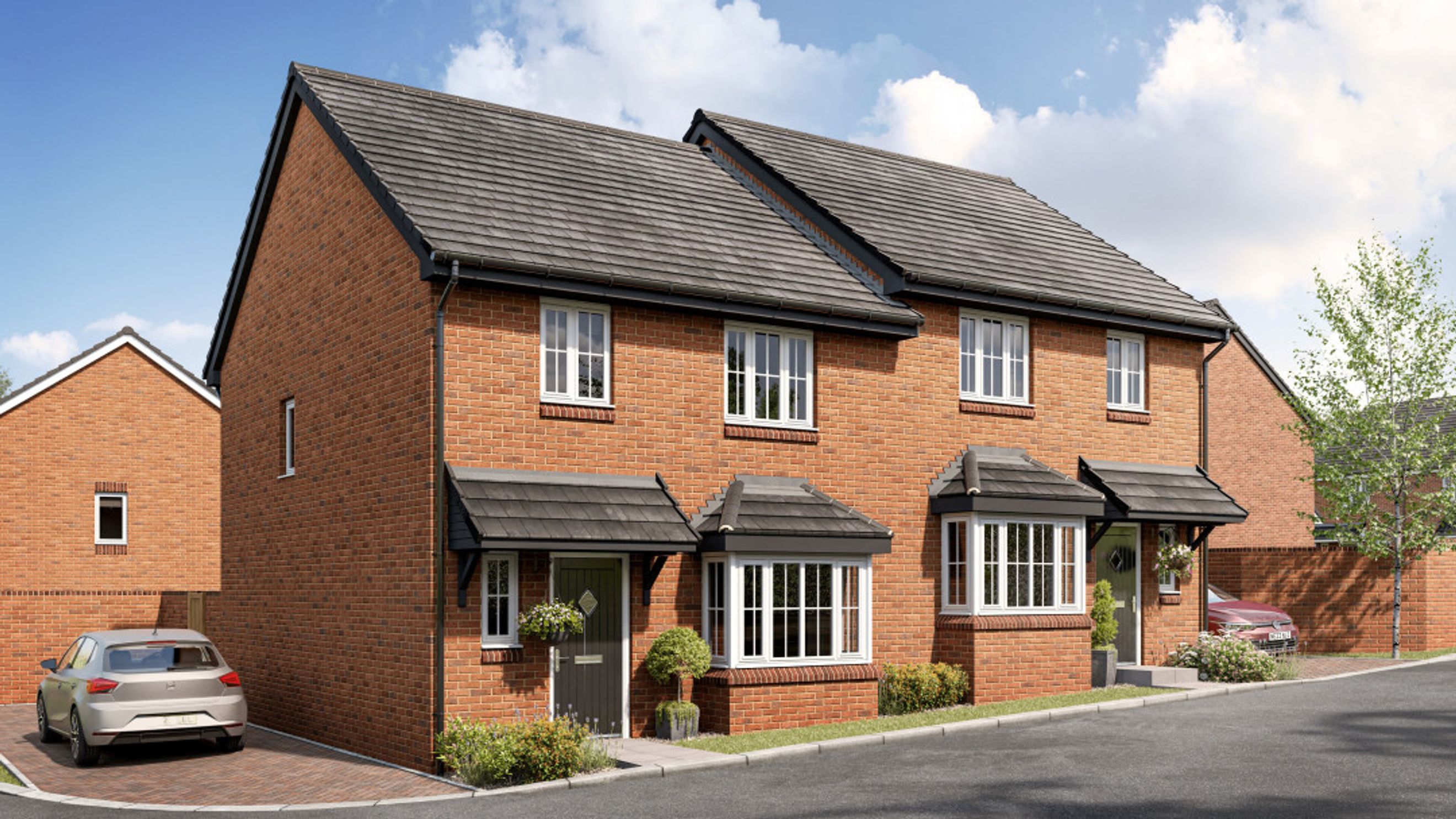 A row of red brick semi-detached houses with bay windows and driveways.