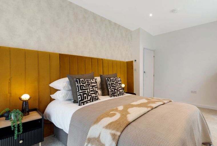 A bedroom with a bed, headboard, and bedside table.