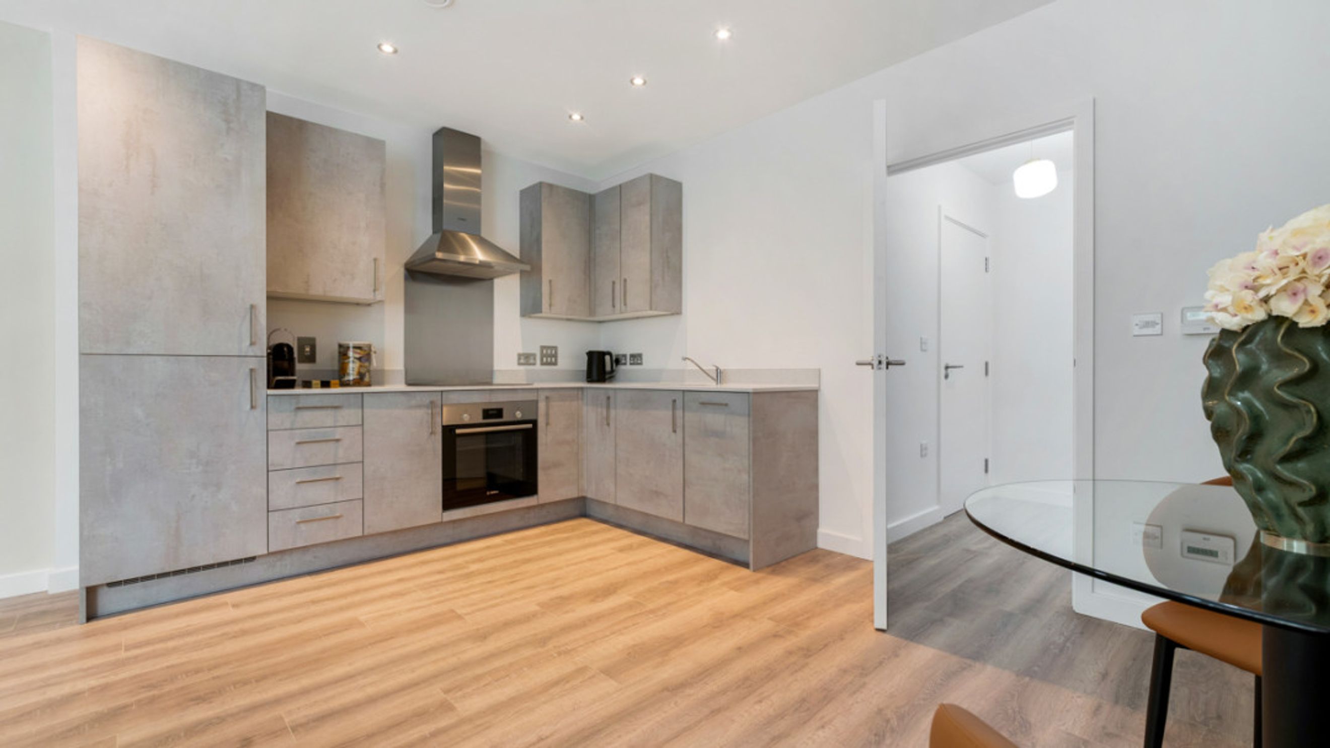 A modern kitchen with grey cabinets, an oven, and a sink.