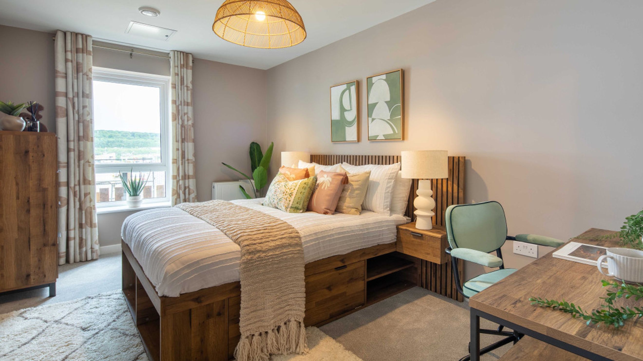 A bedroom with a bed, pillows, a throw blanket, bedside lamps, a desk, and a chair.