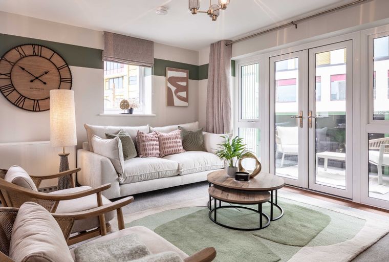 A living room with a sofa, coffee table, chairs, and a large clock on the wall.