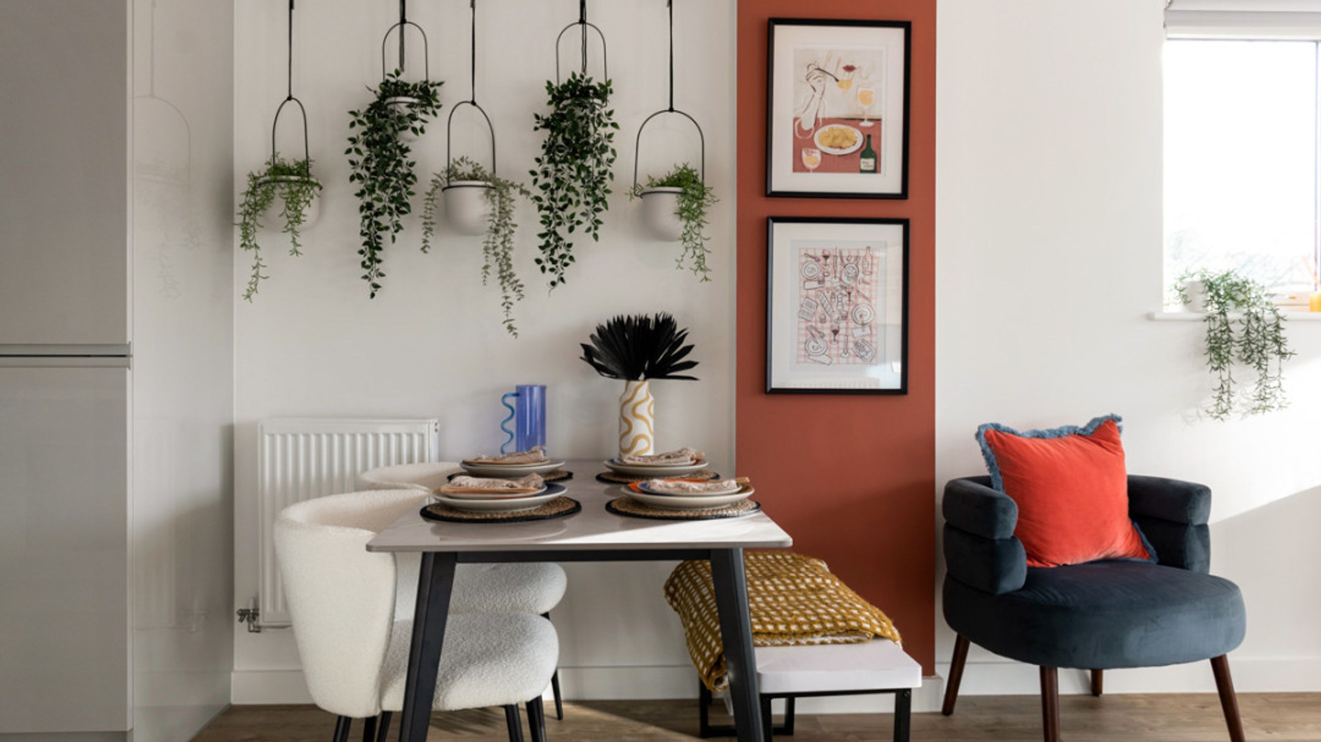 A dining area with a table, chairs, and hanging plants.