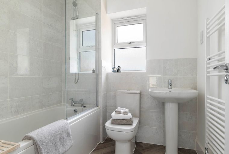 A bathroom with a bathtub, toilet, sink, and towel radiator.