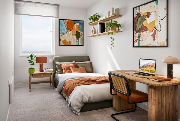 A bedroom with a bed, a desk, and a window.
