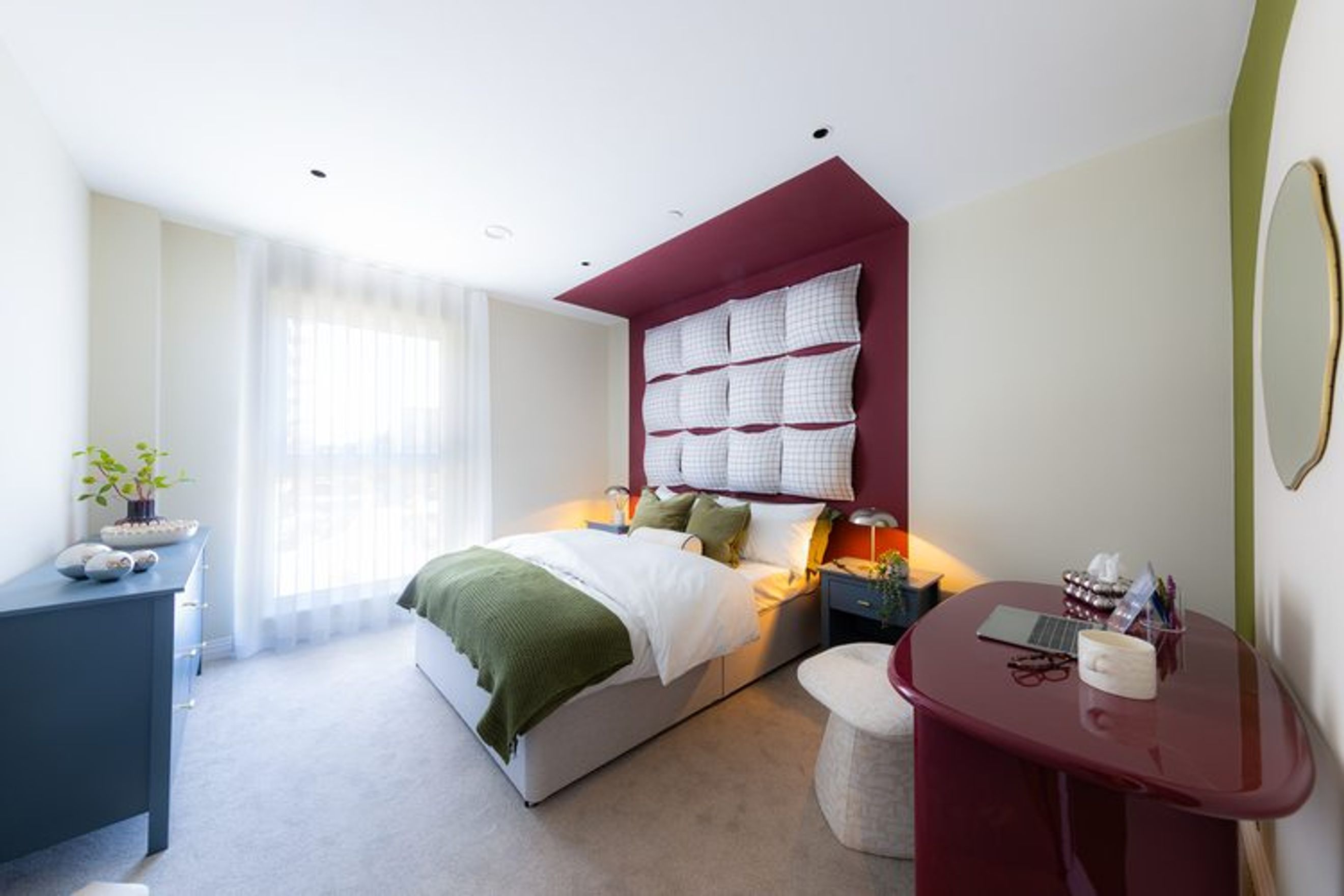 A bedroom with a bed, a dresser, and a desk.