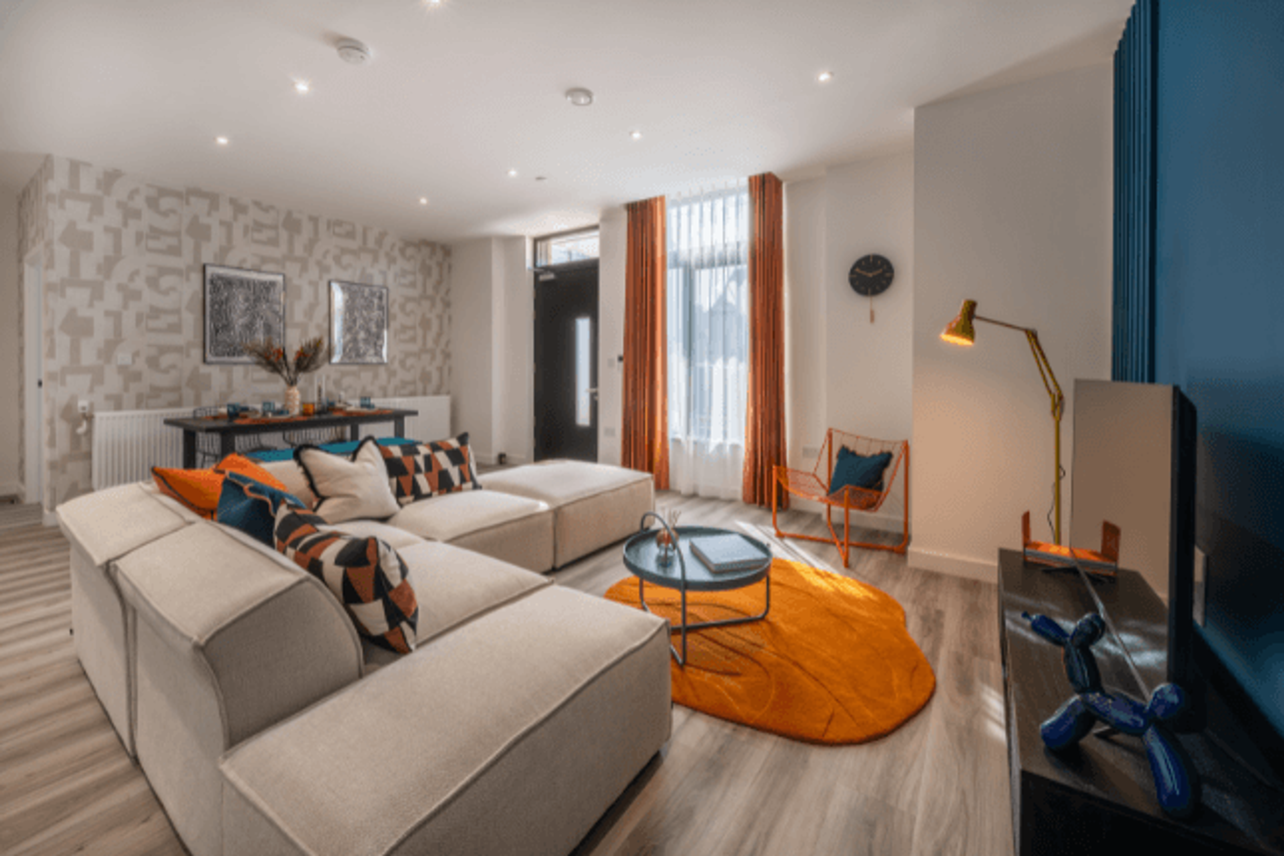 A living room with a sectional sofa, coffee table, and an orange rug.