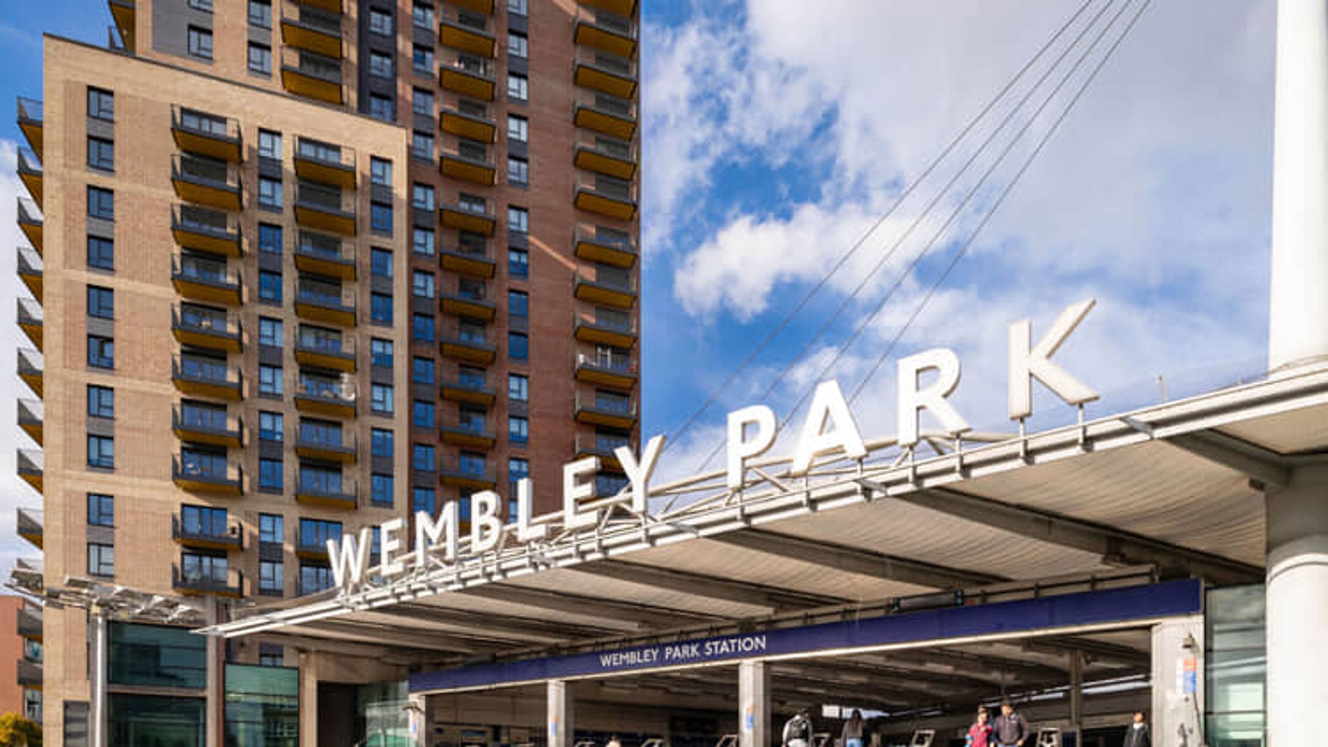 A modern apartment building next to Wembley Park Station with large balconies.