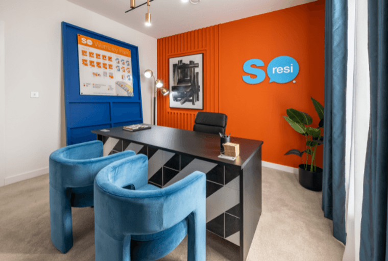 An office with a desk, chairs, and a logo on the wall.