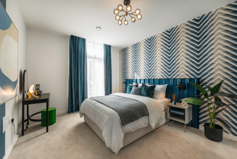A bedroom with a bed, accent wall, and a vanity.
