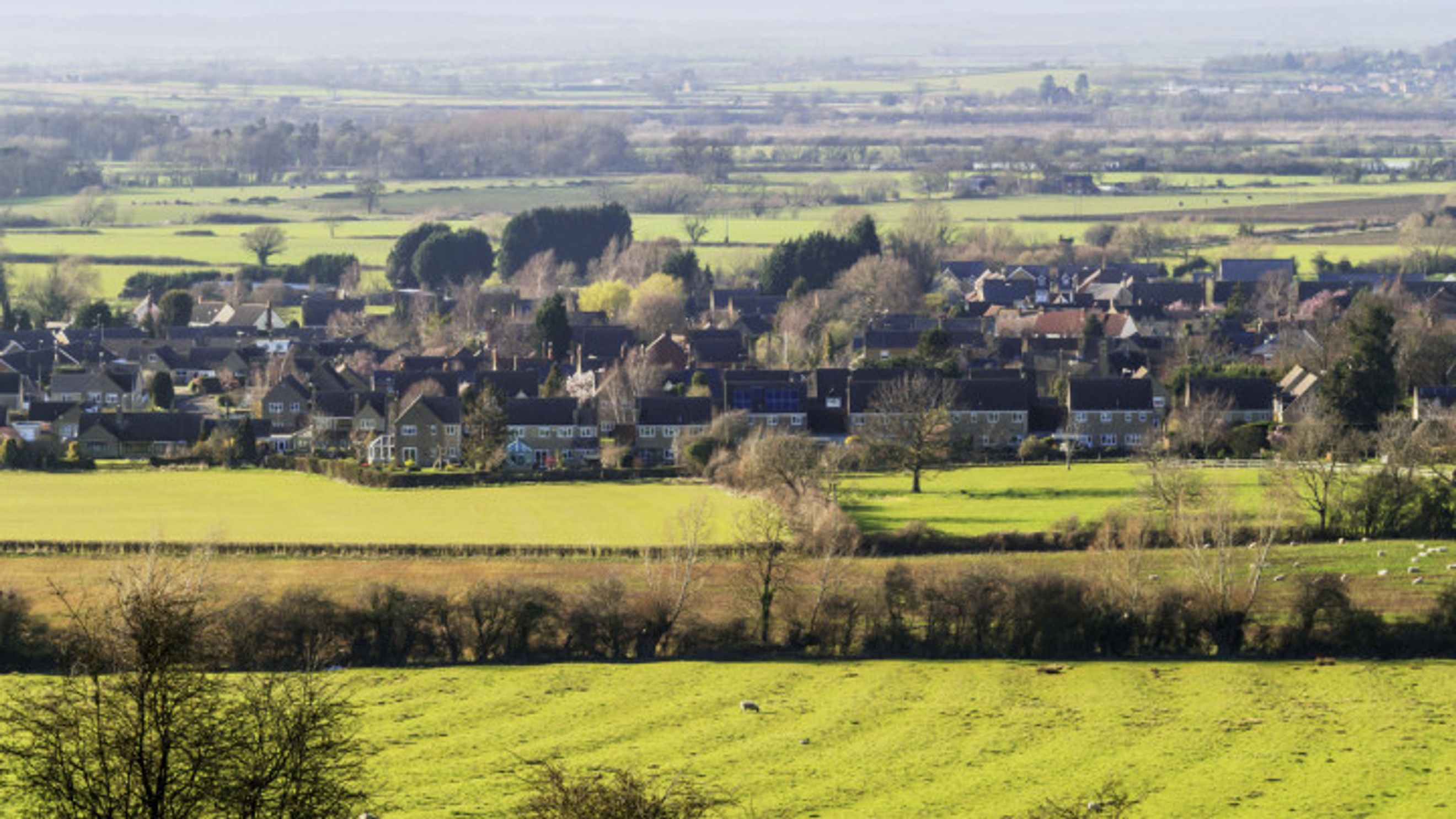 A village with houses and green fields in the distance.