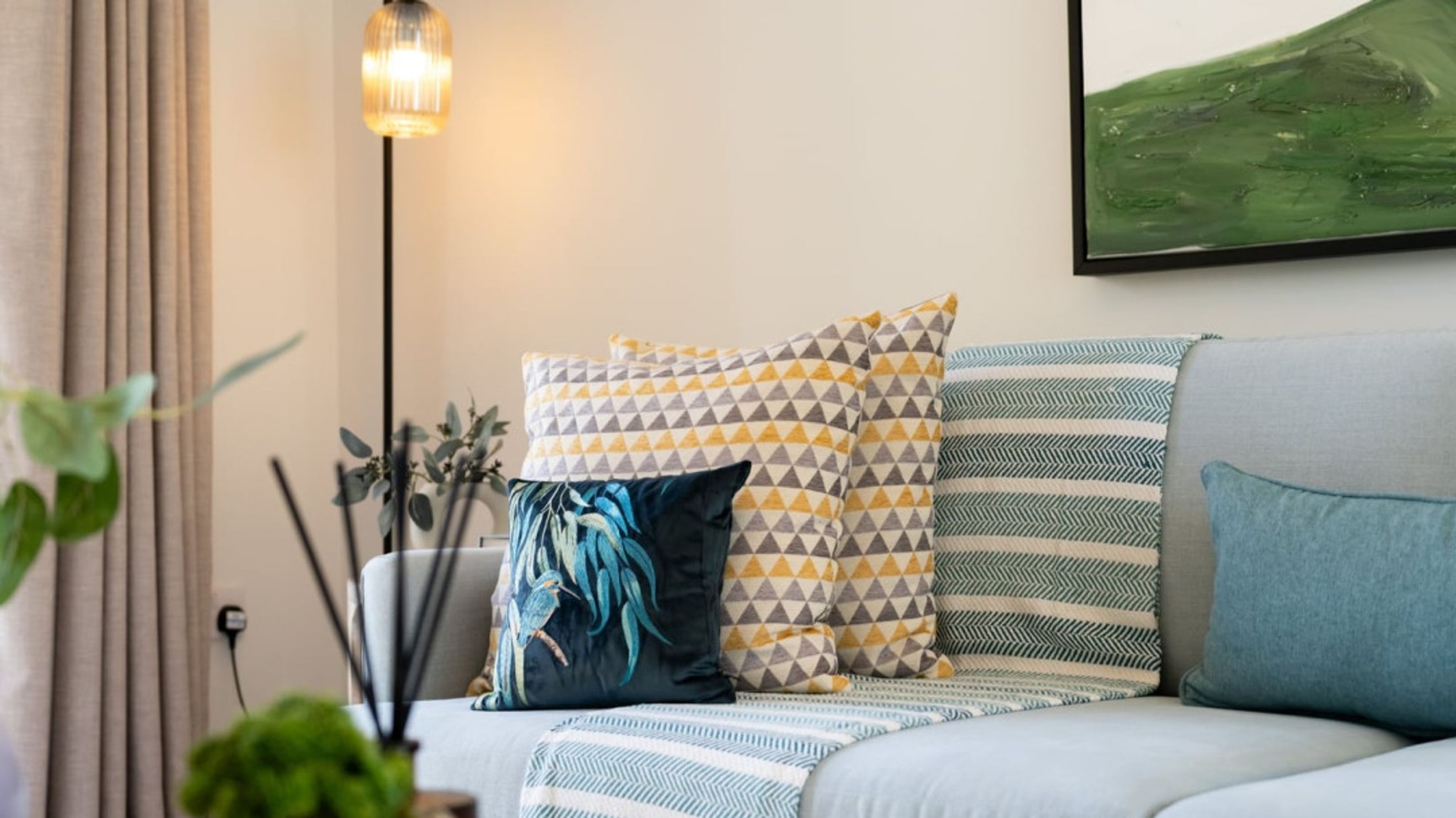 A light blue sofa with several decorative pillows and a throw blanket.