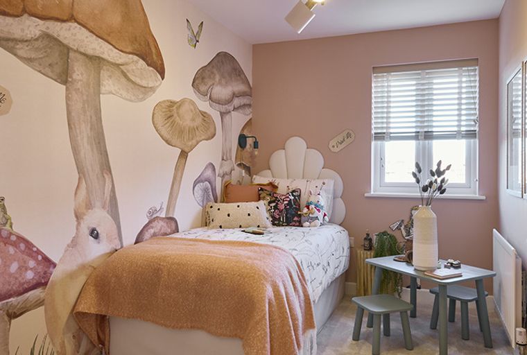 A bedroom with a bed, a mushroom mural, and a small table with chairs.