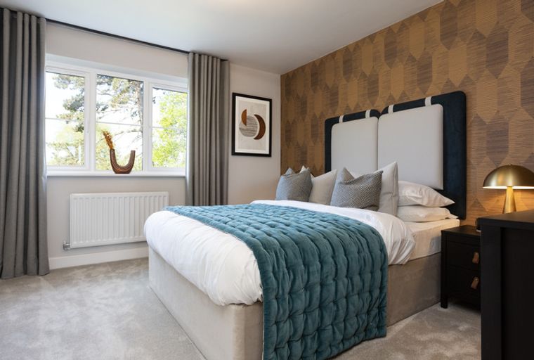 A bedroom with a bed, pillows, a teal blanket, curtains, a window, and a bedside table.