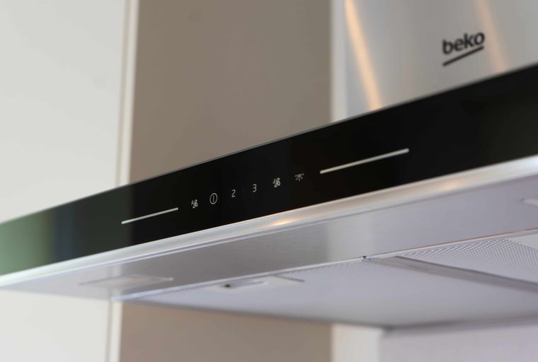A stainless steel Beko range hood with a black touch control panel displaying fan speed and light icons.