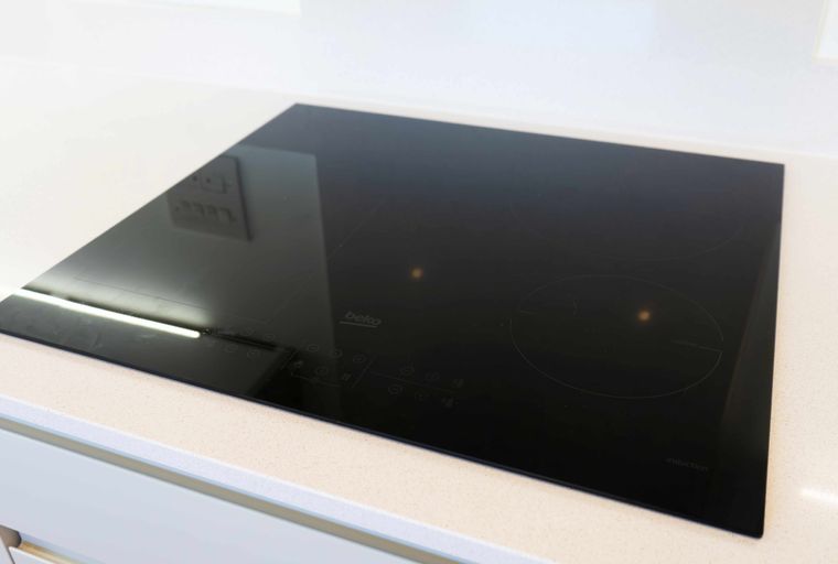 A black induction hob with touch controls on a white countertop.