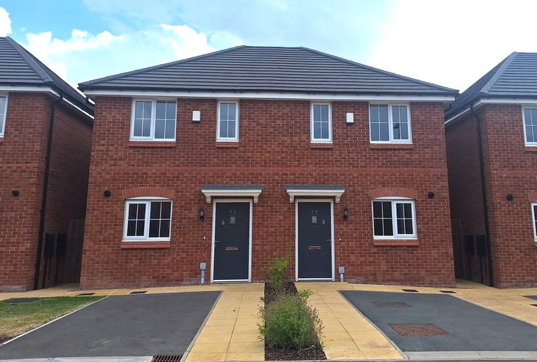 A pair of modern red brick semi-detached houses with dark grey front doors and white-framed windows.