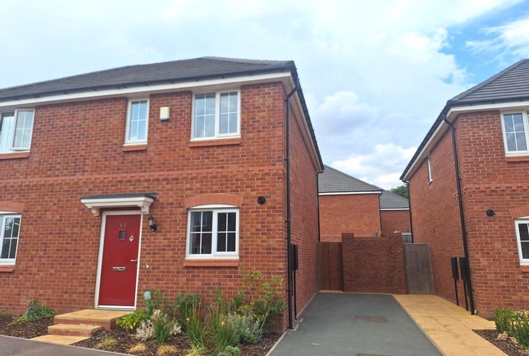 A red brick house with a red front door and white windows.