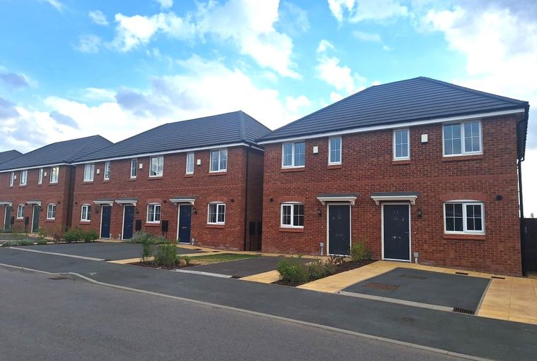 A row of new brick townhouses with dark roofs and white windows.