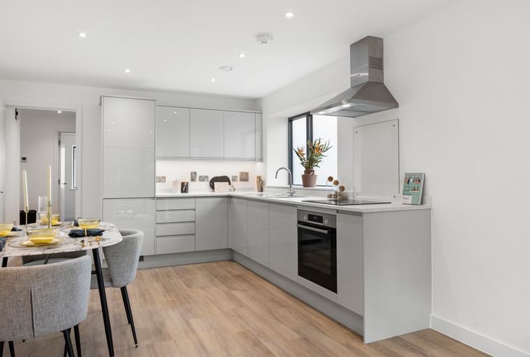 A modern kitchen and dining area with grey cabinets, a dining table, and chairs.