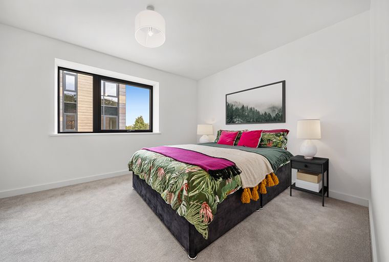 A bedroom with a bed, pillows, a blanket, a nightstand, and a window.