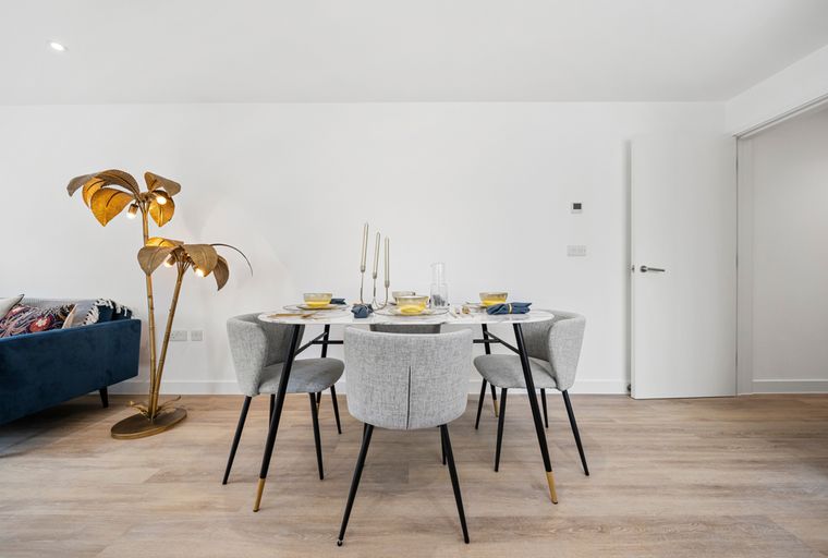 A dining table with four chairs and a palm leaf floor lamp.