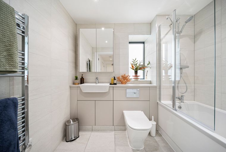 A modern bathroom with a sink, toilet, bathtub, and a towel warmer.