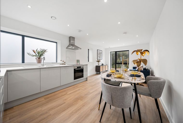 A modern kitchen and dining area with sleek cabinets, a marble-top dining table, and a unique gold lamp.