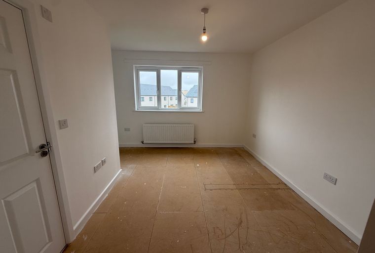 A room with a window, radiator, and electrical outlets.