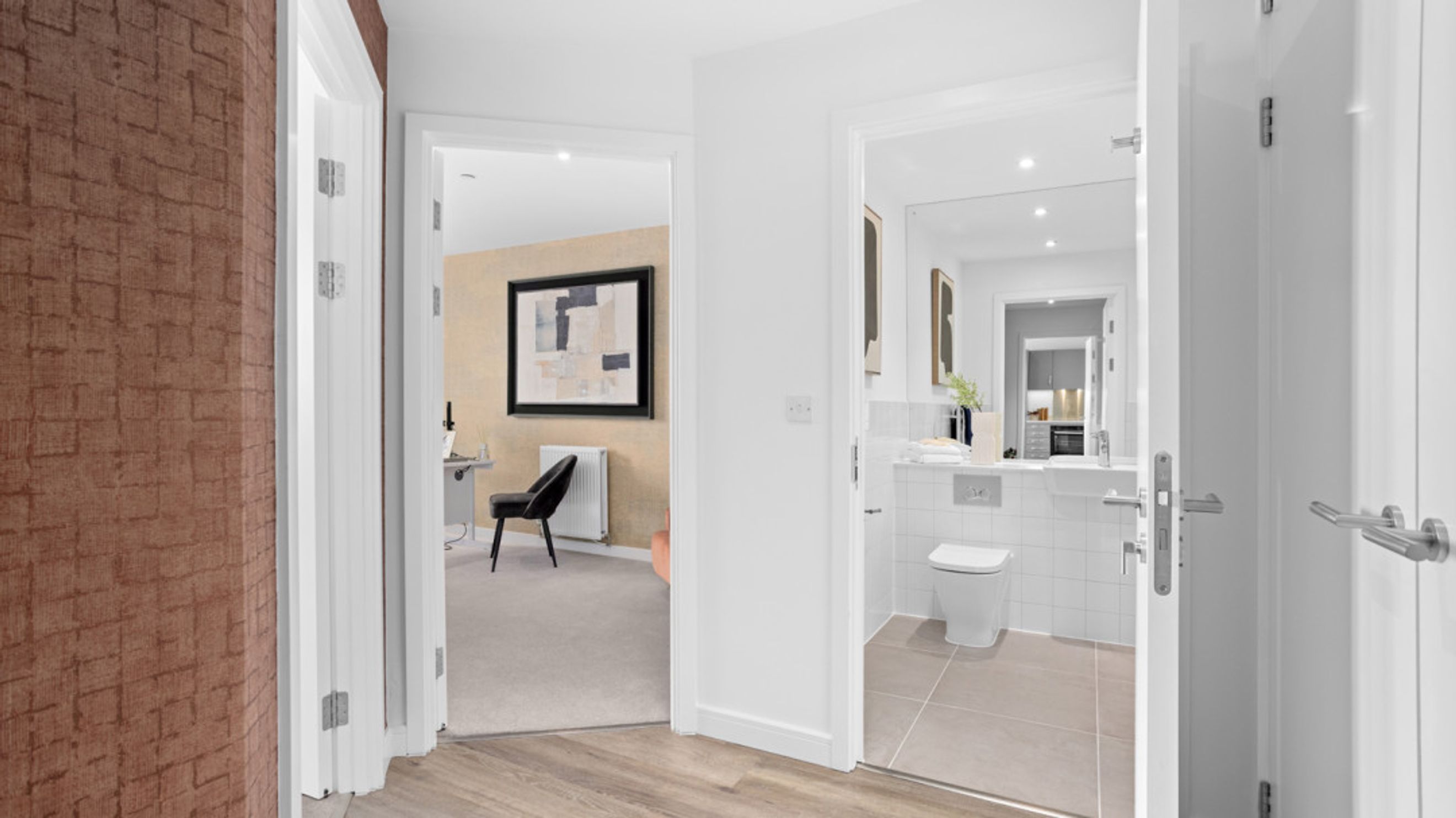 A hallway with two open doorways, one leading to a home office and the other to a bathroom.