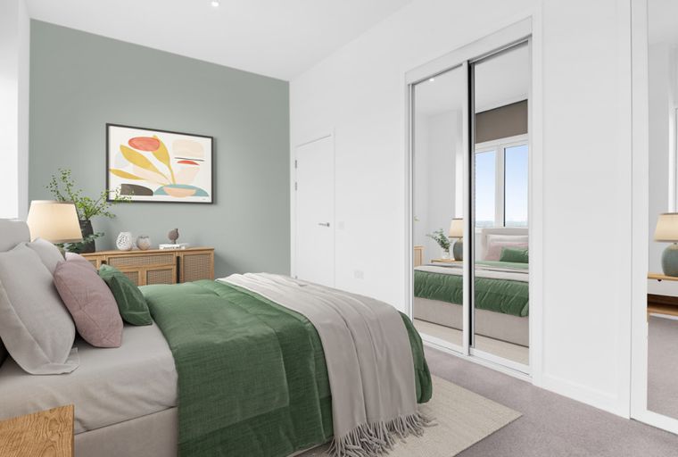 A bedroom with a bed, mirrored wardrobe, and a dresser.
