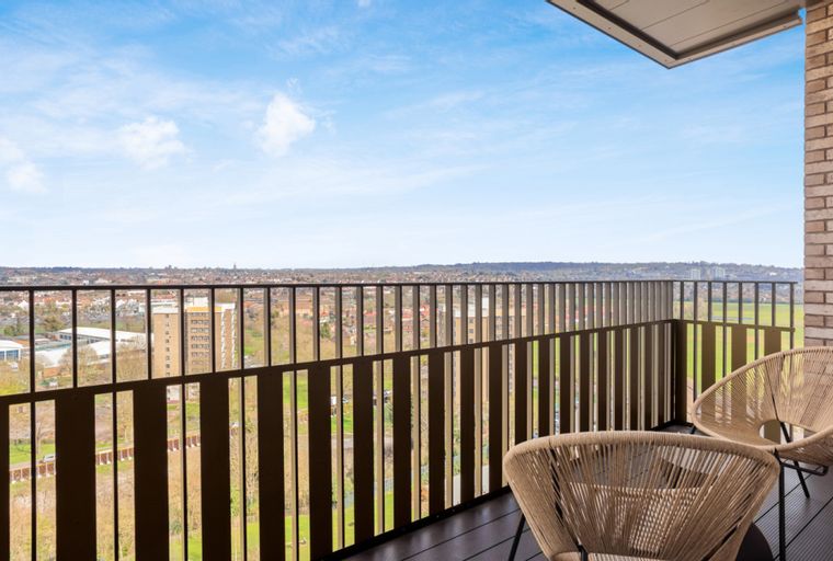A balcony with two chairs overlooking a cityscape.